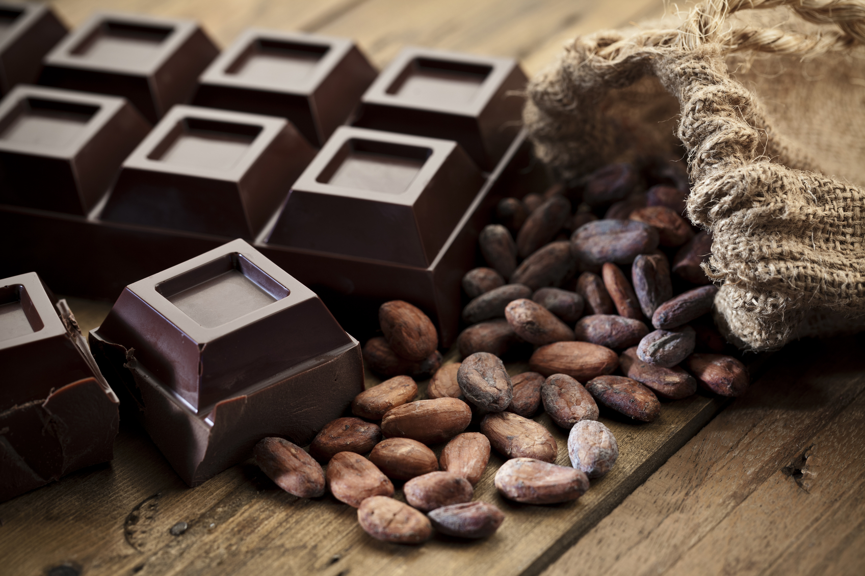 Dark Chocolate with Cocoa Beans on Wood Table